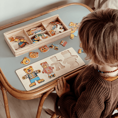 Child playing with wooden bear puzzle and toy set on a table