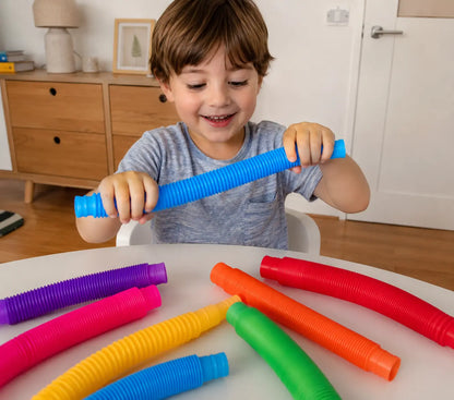 Child playing with colorful plastic tubes on a table in a room.
