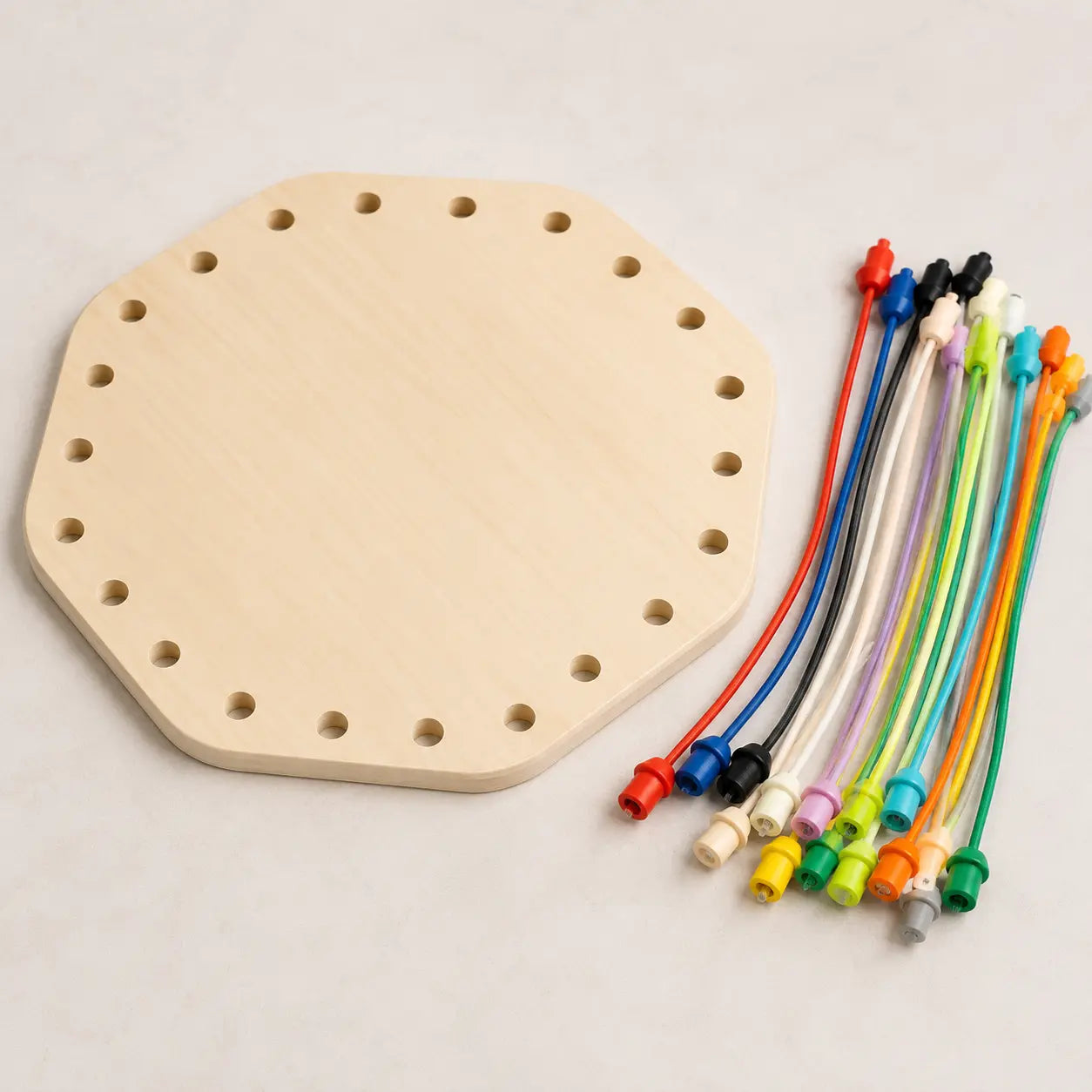 Hexagonal wooden lacing board with 22 holes displayed beside colourful threading cords for fine motor and coordination play.