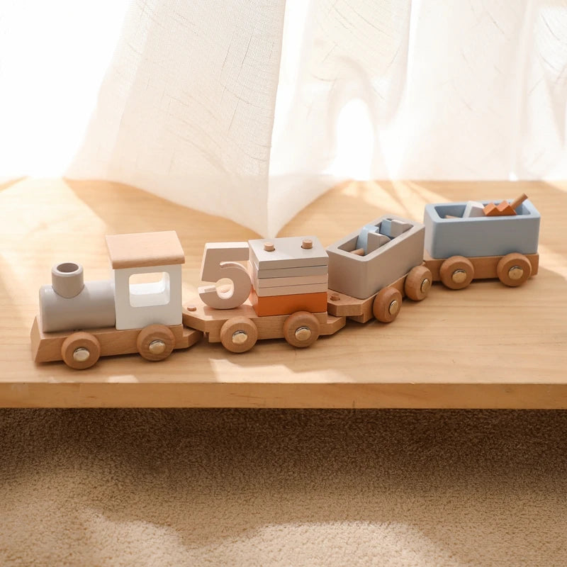 Wooden toy train set on a wooden surface with a soft white curtain in the background.