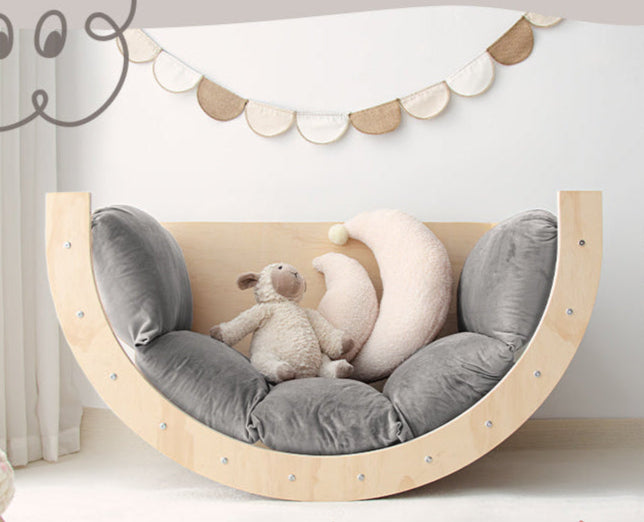 Play area with a wooden multi functional arch, gray cushions, and toys 