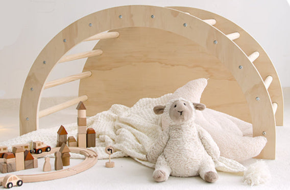 Wooden toy arch with a plush lamb toy and wooden train set