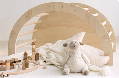 Wooden toy arch with a plush lamb toy and wooden train set
